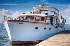 a man standing on top of a boat docked at a pier with an american flag