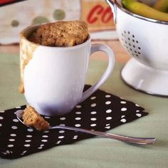 a cup filled with coffee next to a bowl of bananas