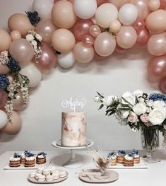 a table topped with cakes and desserts next to balloons