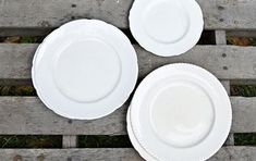 three white plates sitting on top of a wooden pallet