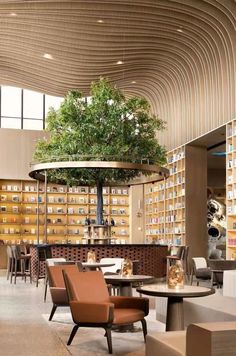 the inside of a restaurant with tables, chairs and a large tree in the center