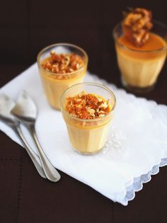 two desserts are sitting on a napkin with spoons next to them and one is topped with nuts