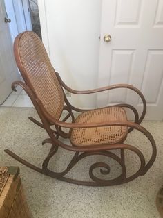 a wooden rocking chair sitting on top of a floor next to a white door in a room