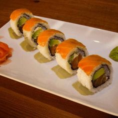 sushi rolls on a white plate with sauce and garnish