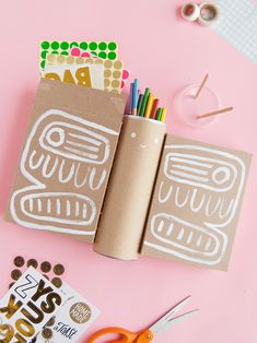 an open book sitting on top of a pink table next to scissors and other items