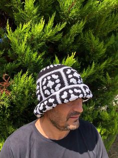 a man wearing a black and white knitted hat sitting in front of some trees