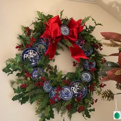 a christmas wreath hanging on the wall next to other holiday decorations and greenery with red bows