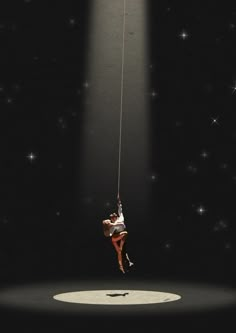 a person hanging from a rope in the dark