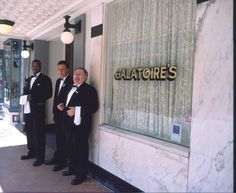 three men in tuxedos standing next to a wall with the words galatories on it