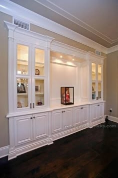 an empty room with white cabinets and wood floors