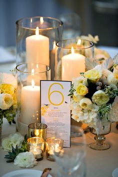 the table is set with candles, flowers and menu cards for an elegant wedding reception