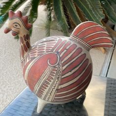 a statue of a giraffe on display in front of a palm tree and building