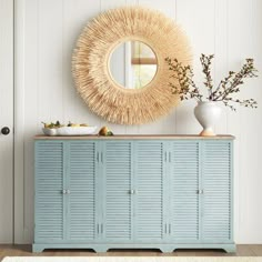 a blue cabinet with drawers and a round mirror on the wall above it in a white room