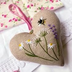 a heart shaped pillow with flowers and a bee on it