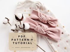 a pair of pink bow headbands next to cotton flowers on a white background