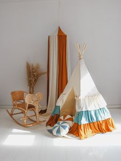 a teepee sitting on top of a white floor next to a rocking chair