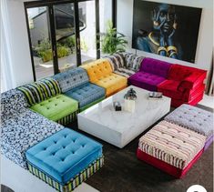 a living room filled with lots of colorful couches and tables in front of large windows