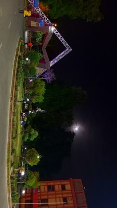 an overhead view of a street and trees at night with lights on the building next to it