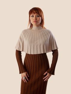 a woman standing with her hands on her hips wearing a brown and white sweater dress