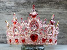 For adults, not suitable for children.  This HUGE crown is too heavy for children.   The crown is adorned with glass rhinestones, crystal beads, and resin hearts on a gold base.  There are loop ends to attach your crown with pins or elastic.   The crown weighs 13.5 ounces (nearly a pound).  The diameter across is 6.5 inches.  It is 5 inches tall at its highest point.   Ships in a box for safe travels! Shipping Details: All items will be shipped First Class by the United States Postal Service. An Bridget Cosplay, Red Heart Crown, Hot Pink Crown, Pink Crown-shaped Wedding Jewelry, Elegant Pink Crown-shaped Jewelry, Queen Of Hearts Crown, Gold Crown With Red Jewels, Disney Princess Gowns, Resin Hearts