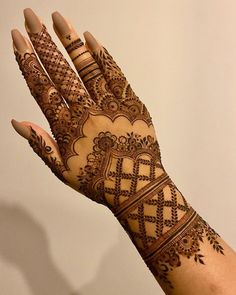 a woman's hand with henna tattoos on it, showing the intricate design