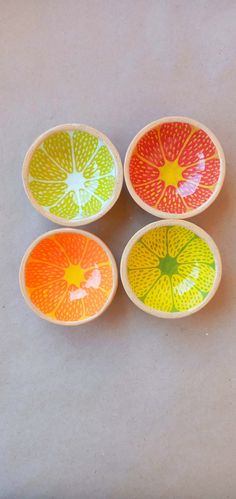 four colorful bowls sitting on top of a white table next to an orange and yellow object