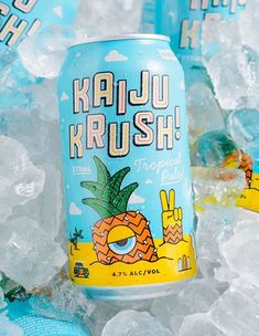 two cans of kaju kurush on ice with blue and yellow balls in the background