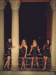 four beautiful young women standing next to each other in front of some tall white pillars