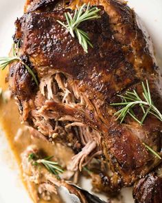 roast beef with gravy and rosemary garnish served on a white plate