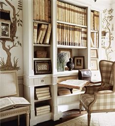 a room with bookshelves, chairs and pictures on the wall in front of it