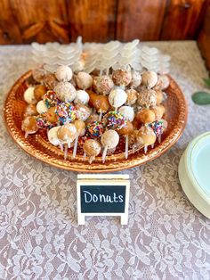 there are many donuts on the plate with sprinkles in them and a sign that says donuts