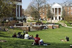 people sitting on the grass in front of a building