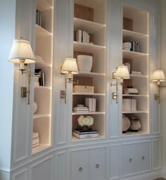 a white bookcase with two lamps on each side and several books in the back