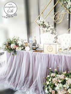 the table is covered with purple tulle and has flowers on it, including roses