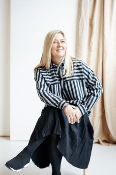 a woman in black and white striped shirt sitting on a chair with her legs crossed