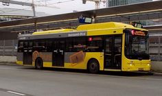 a yellow bus is parked on the side of the road in front of an overpass