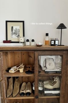 a wooden cabinet with shoes and other items on the top shelf next to a lamp