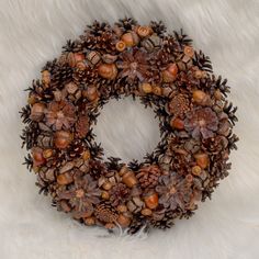 a wreath made out of pine cones and acorns on a white fur background