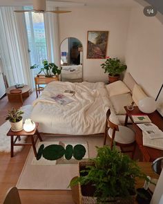 a bed room with a neatly made bed and lots of plants on the floor next to it