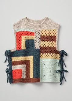 a crocheted sweater with tassels on the sides and an object in the middle