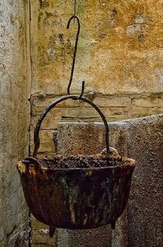 an old rusted bucket hanging from the side of a building with a rusty handle