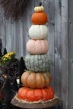 a stack of pumpkins sitting on top of each other in front of a fence