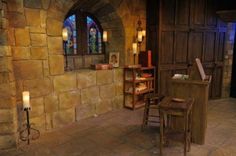 the inside of a building with stone walls and stained glass windows, including a desk