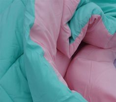 a pink and blue comforter is laying on the ground