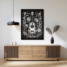 a black and white painting on the wall above a wooden sideboard with a guitar