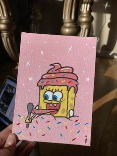 a hand holding up a pink card with an image of a cupcake on it