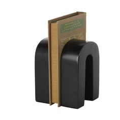 a black bookend with an open book on it's side and a brown book in the middle