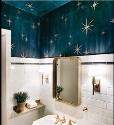 a bathroom with stars painted on the ceiling and white tile walls, along with a gold framed mirror