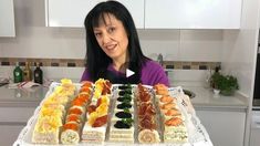 a woman sitting in front of a platter filled with different types of sushi