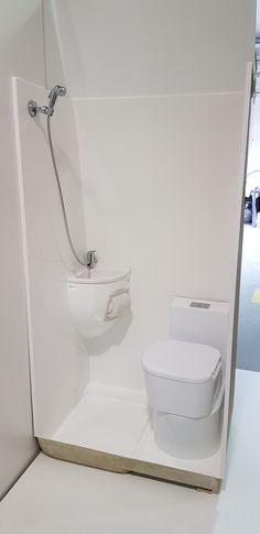 a white toilet sitting in the corner of a room next to a shower head and seat